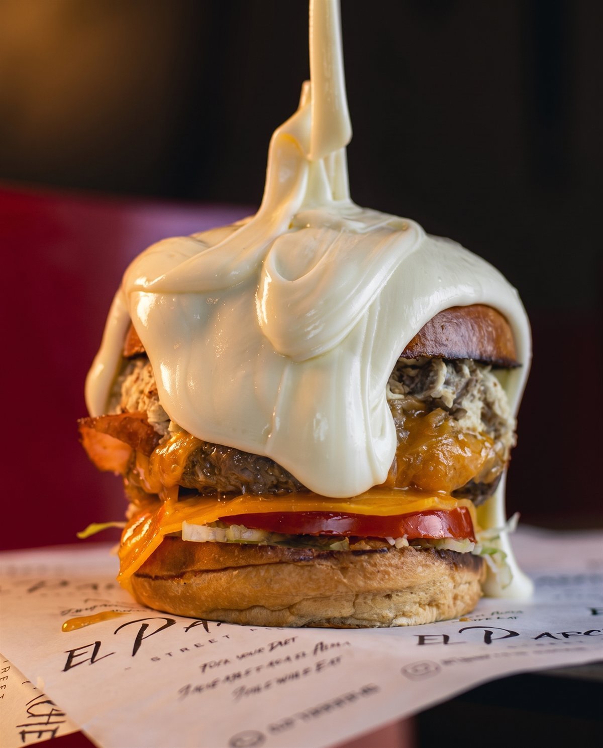 Melted mozzarella pouring in a cascade over an El Parche burger